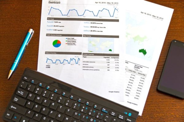 Case Study - Documents with charts and laptop on a brown table